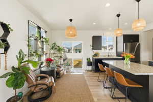 Kitchen with dark cabinetry, decorative light fixtures, freestanding refrigerator, light wood-type flooring, and a kitchen bar