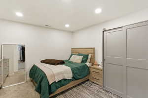 Bedroom with light colored carpet, a closet, and recessed lighting