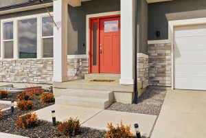 Doorway to property featuring stone siding, stucco siding, and an attached garage