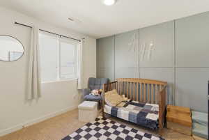 Bedroom featuring carpet flooring, a textured ceiling, a decorative wall, and a nursery area