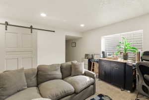 Living area featuring a barn door, light carpet, an office area, recessed lighting, and a textured ceiling