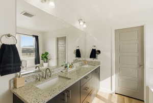 Bathroom with double vanity, light wood-type flooring, and a tub