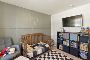 Bedroom featuring a nursery area, a decorative wall, a textured ceiling, and carpet floors