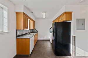 Kitchen with white appliances, backsplash, electric panel, light stone counters, and wood finish cabinetry