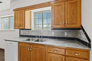 Kitchen featuring wood finish cabinets, dishwasher, and backsplash