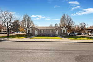 Single story home featuring a front lawn, brick siding, and roof with shingles