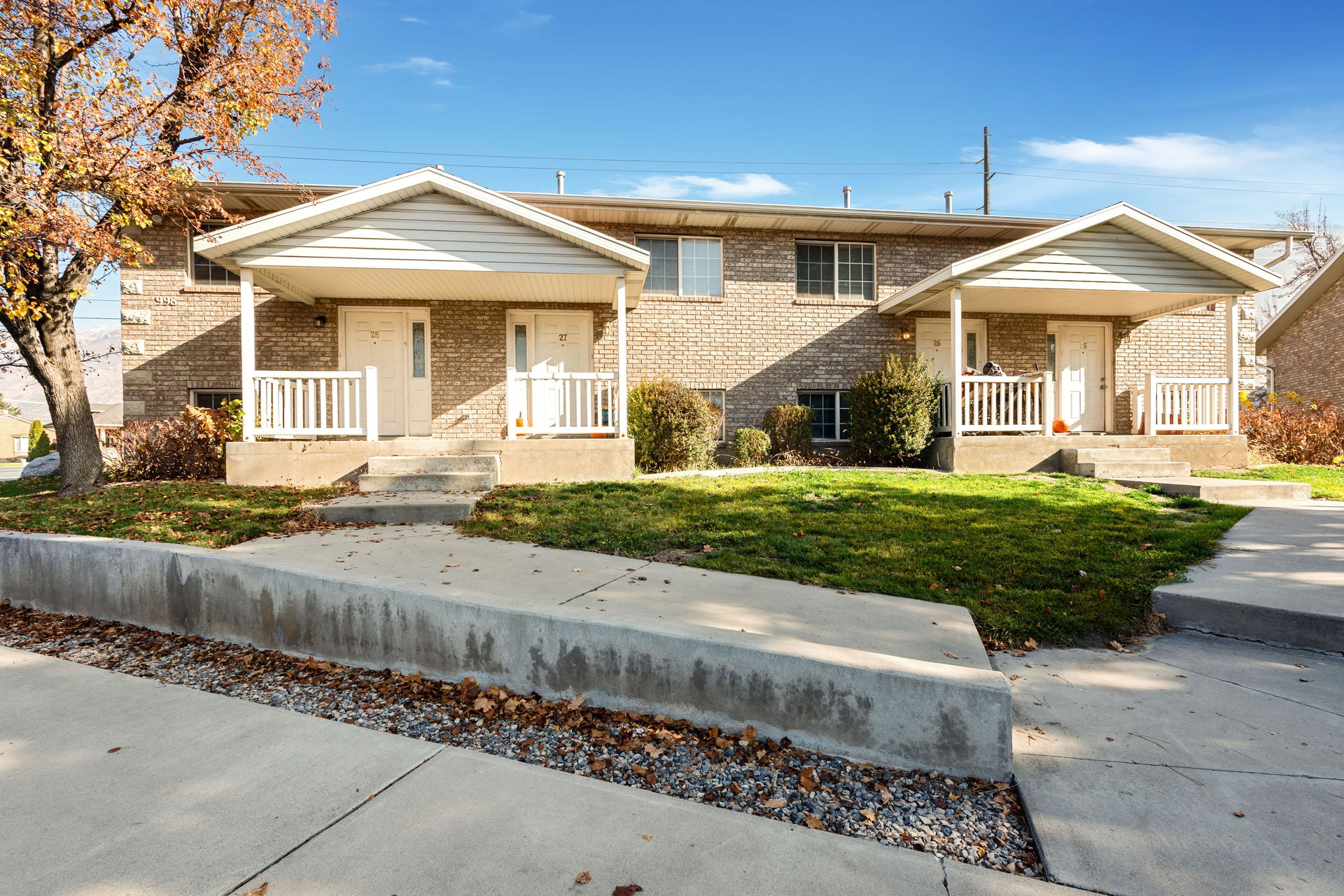 Tri-level home featuring covered porch, brick siding, and a front lawn