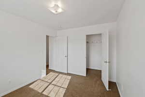 Unfurnished bedroom featuring a walk in closet and carpet flooring