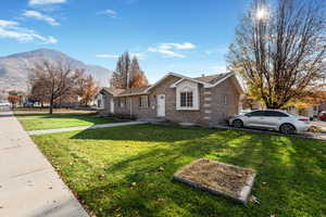 View of front of property with brick siding, a mountain view, and a front lawn