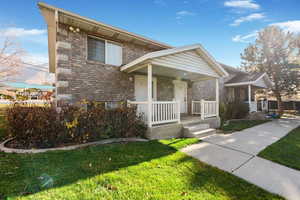 View of front of house featuring brick siding, covered porch, and a front yard