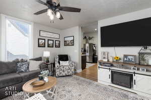 Living area with light wood-type flooring, a ceiling fan, a fireplace, and a textured ceiling