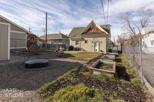 Rear view of house with a patio area, a fenced backyard, a fire pit, a playground, and a vegetable garden