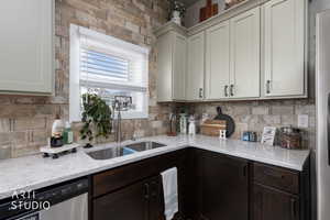 Kitchen with light stone counters, stainless steel appliances, dual tone cabinets, and tasteful backsplash