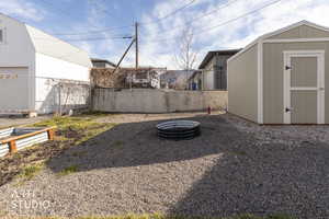 Fenced backyard with an outdoor fire pit and a storage shed