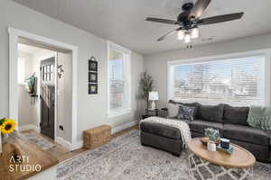 Living room with a ceiling fan, light wood finished floors, plenty of natural light, and a textured ceiling