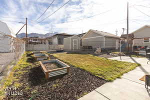 Fenced backyard featuring a vegetable garden and a storage shed