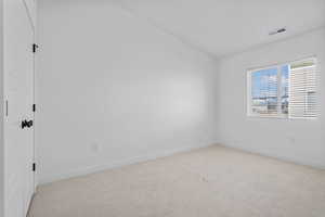 Spare room featuring light carpet and lofted ceiling