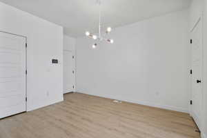 Unfurnished dining area featuring hanging lights and light wood-style floors