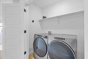 Laundry area with separate washer and dryer and wood finished floors