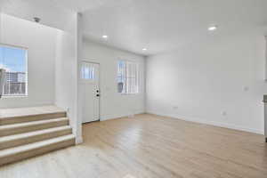 Foyer with recessed lighting, a textured ceiling, and light wood-style floors