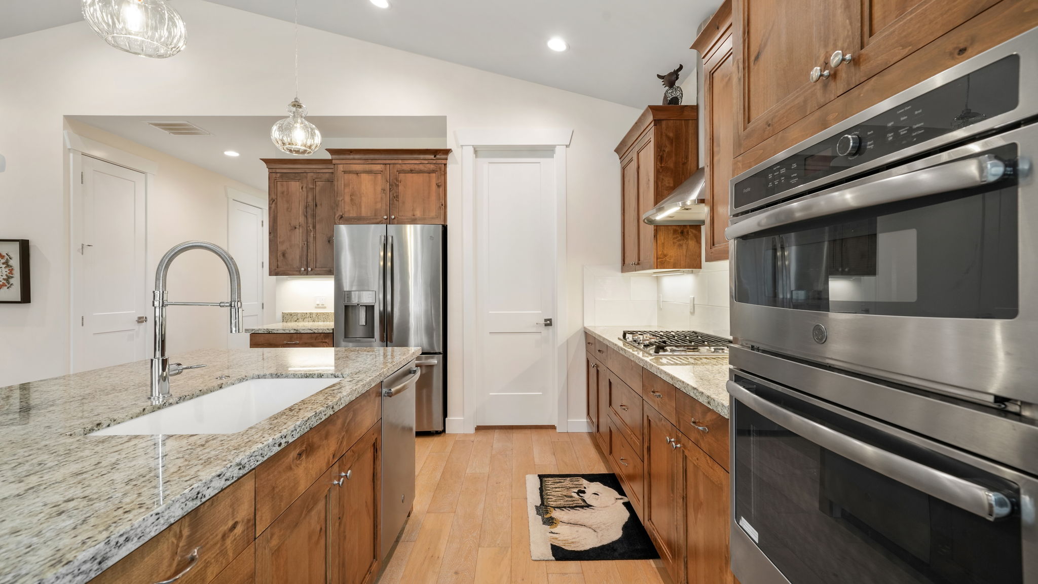 Gourmet kitchen featuring a built-in oven and microwave, gas cooktop, stainless steel appliances, granite countertops, and light wood-finish flooring