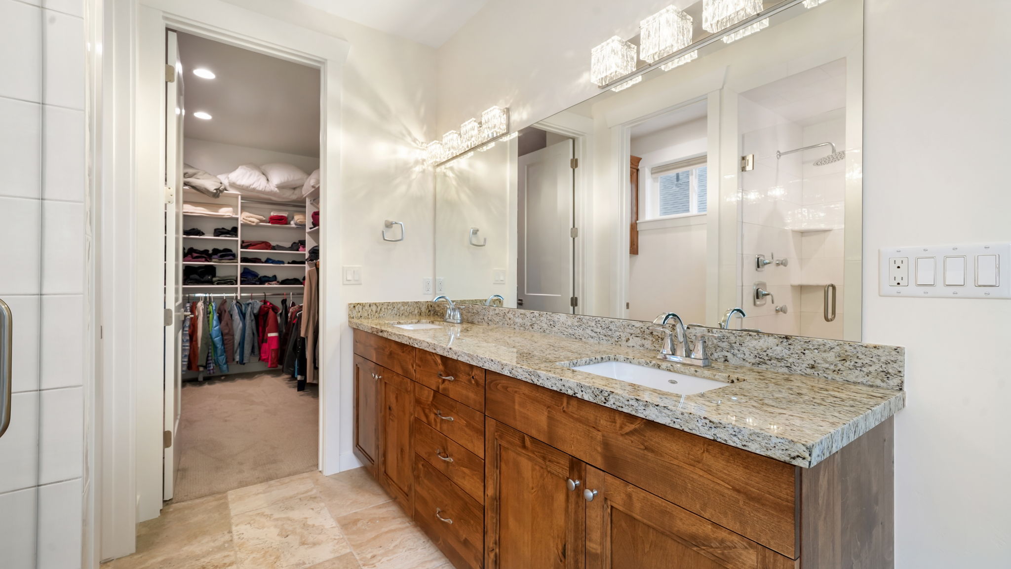 Bathroom featuring a double vanity with stone countertops, undermount sinks, and wood cabinetry