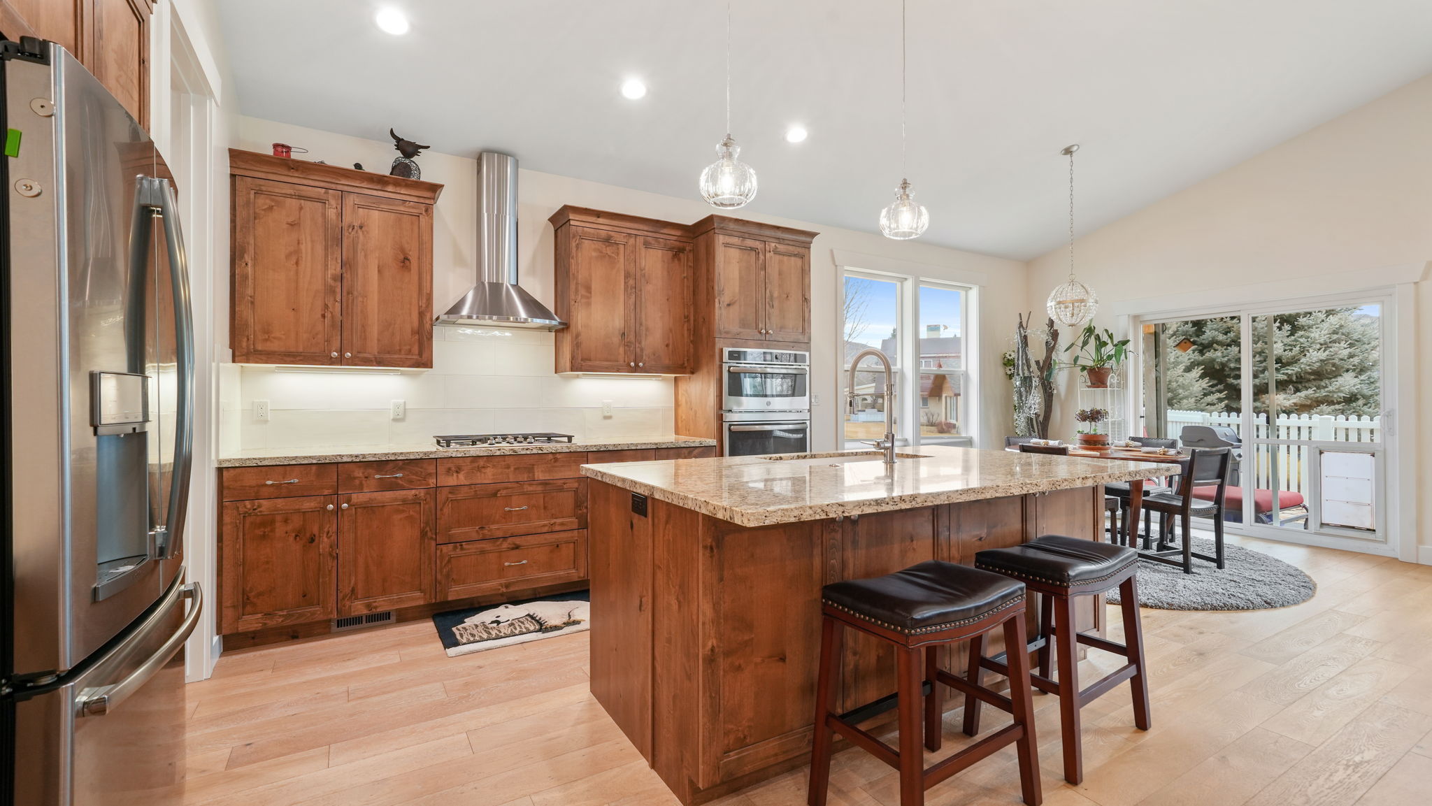 Open-concept kitchen featuring wood-finish cabinetry, stainless steel appliances, and a central island with a stone countertop
