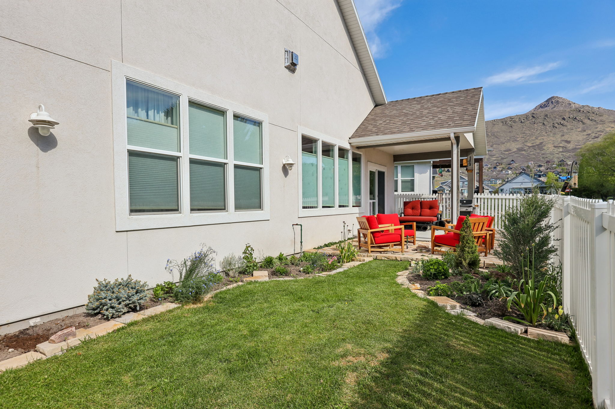 Patio area featuring a covered porch, white picket fence, and a manicured lawn