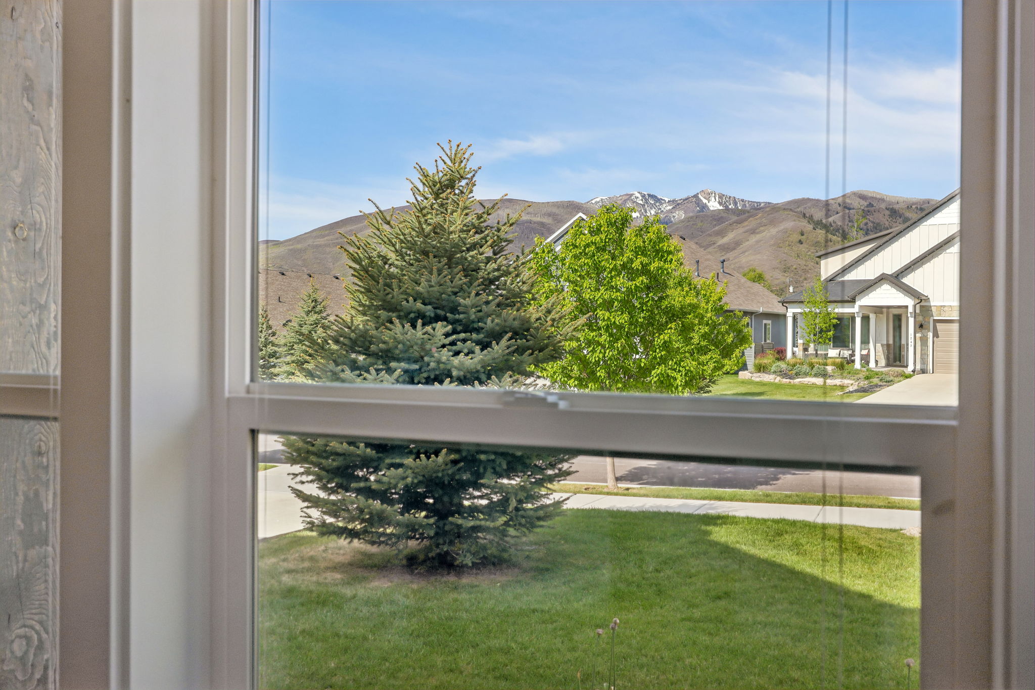 Double-pane window framing mountain scenery with snow-capped peaks
