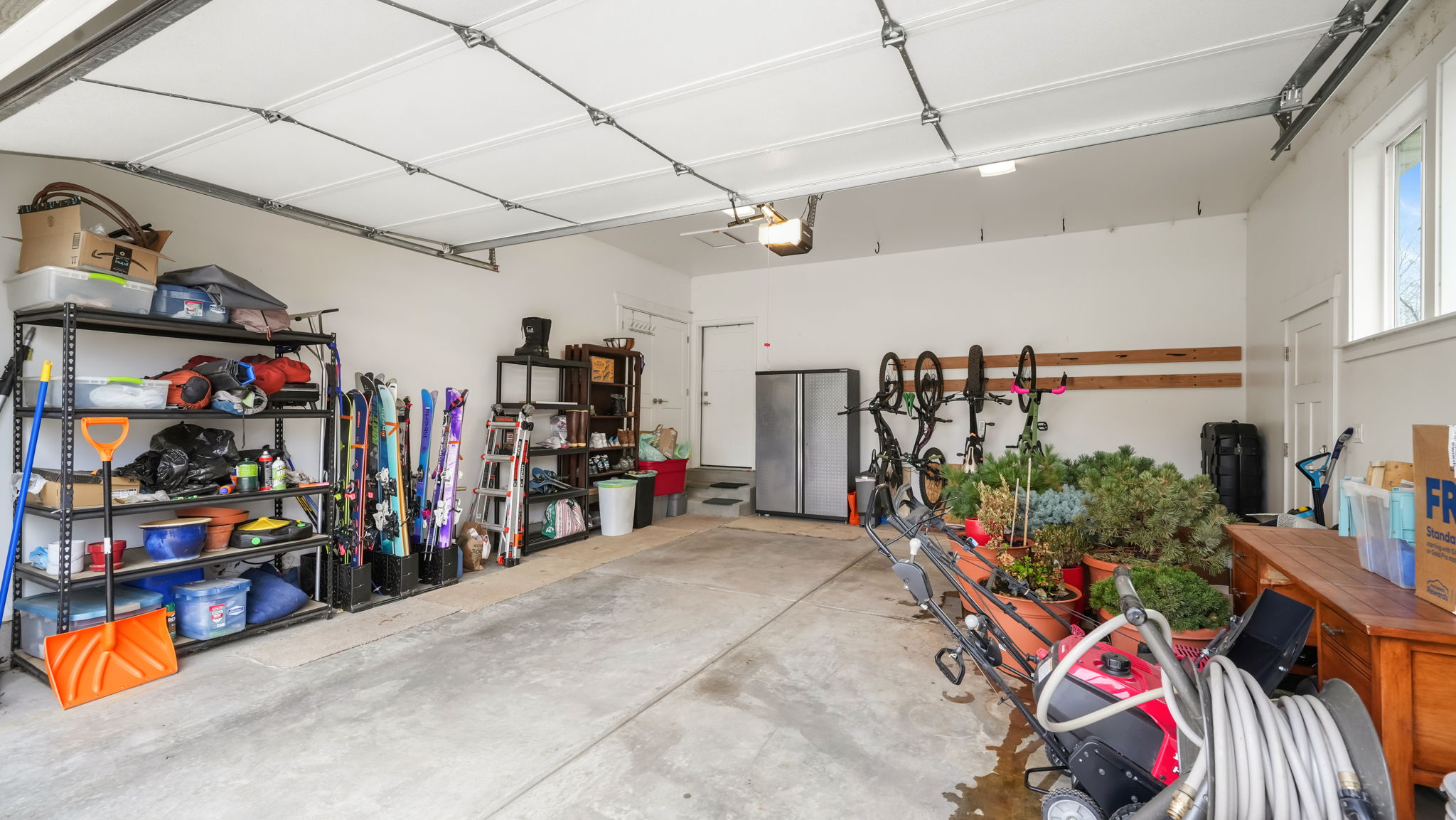 Spacious two-car garage with concrete flooring, white painted walls, and overhead lighting