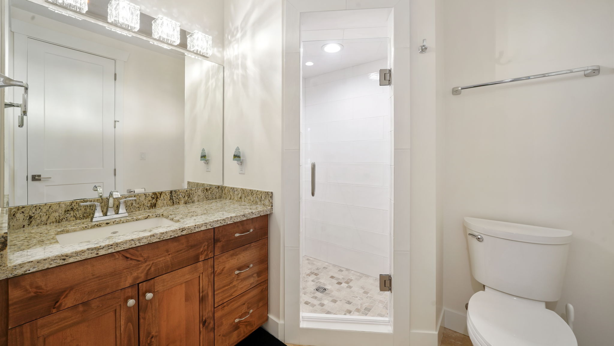 Bathroom featuring a wood-finish vanity with a granite countertop and integrated sink