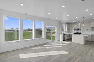 Kitchen featuring decorative light fixtures, a kitchen island, light wood finished floors, and open floor plan