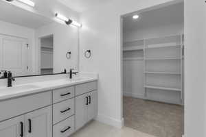 Bathroom featuring a walk in closet, double vanity, light carpet, and recessed lighting