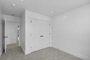Unfurnished bedroom featuring light colored carpet, a closet, and recessed lighting