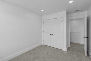 Unfurnished bedroom with light carpet, a closet, and recessed lighting