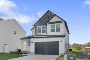 View of front of home featuring an attached garage, board and batten siding, concrete driveway, and a front yard