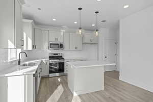 Kitchen with stainless steel appliances, a center island, light wood-type flooring, and decorative light fixtures