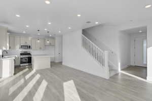 Kitchen featuring stainless steel appliances, a kitchen island, light wood finished floors, and open floor plan