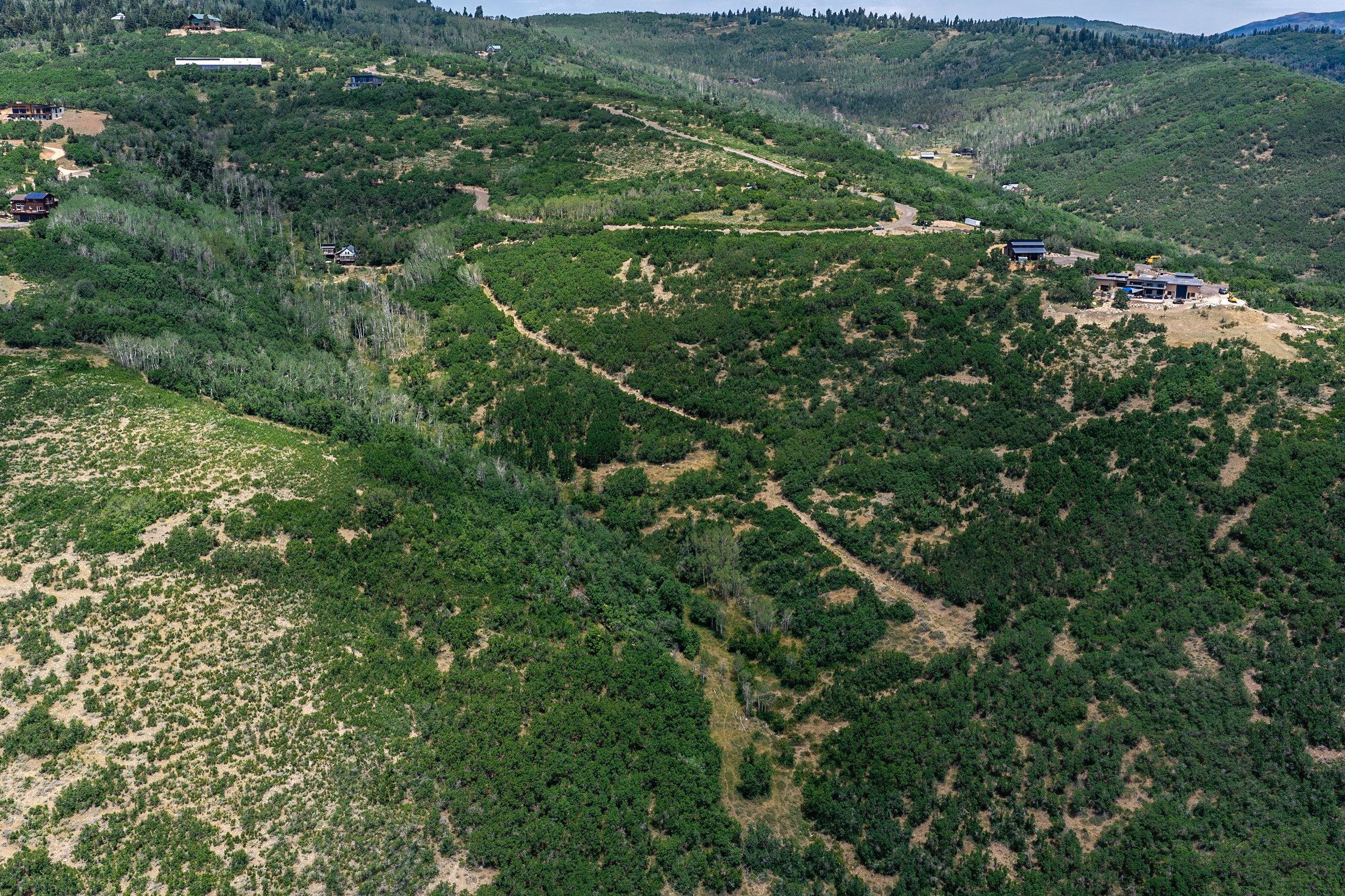 Expansive mountainous terrain featuring dense natural foliage and scattered residences