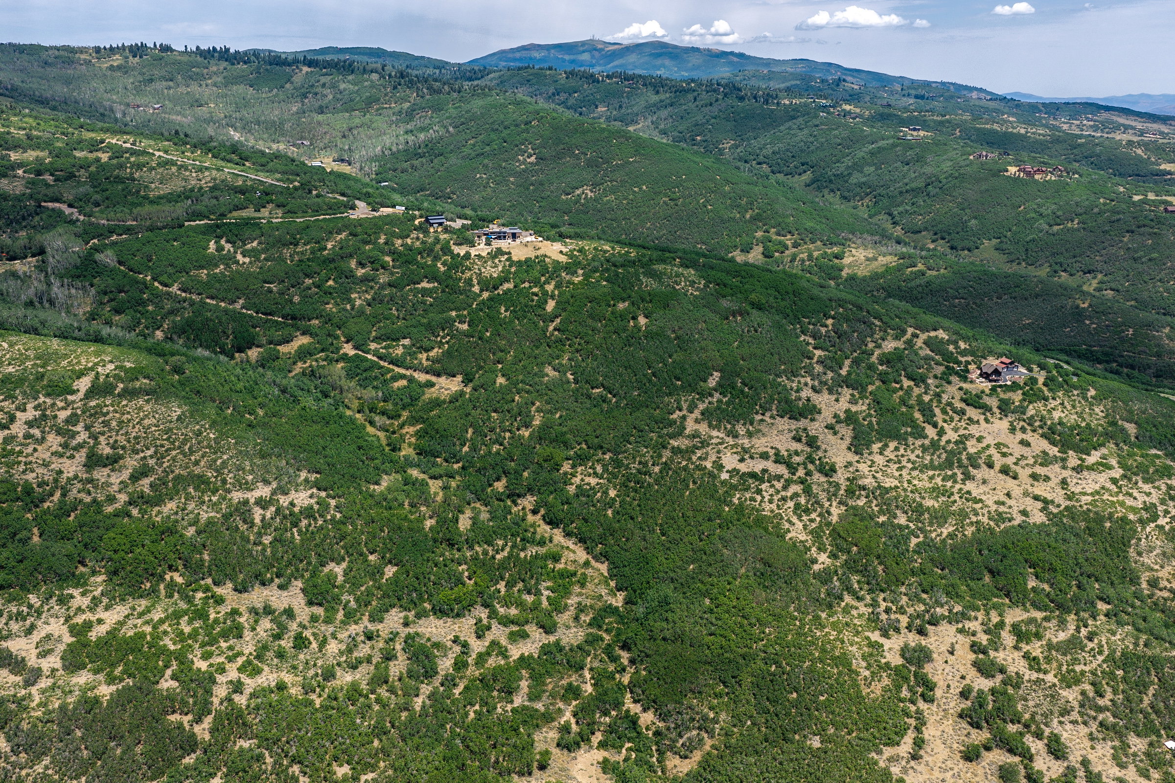 Expansive mountain landscape featuring varied topography, distant mountain ranges, and scattered residential properties