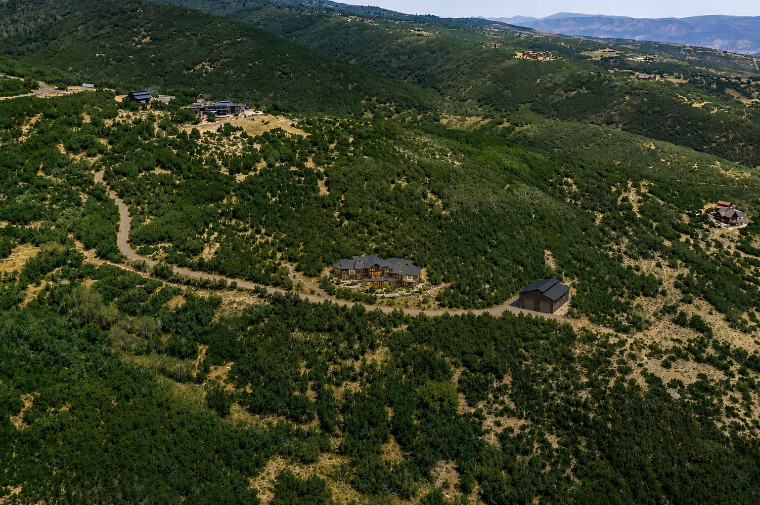 Expansive hillside property featuring a main residence, a secondary building, and a winding driveway