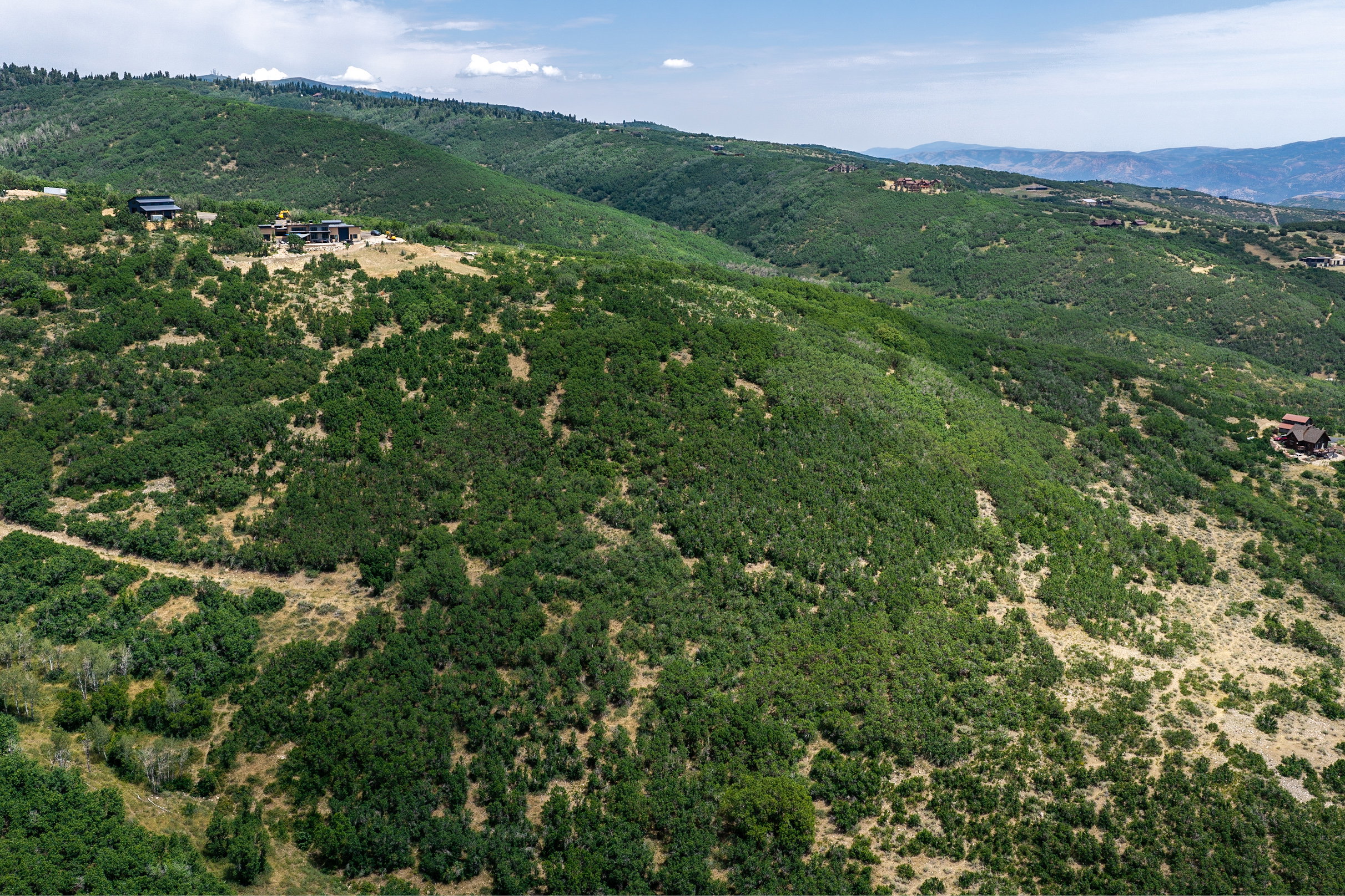 Expansive mountainous terrain featuring lush green foliage and distant structures