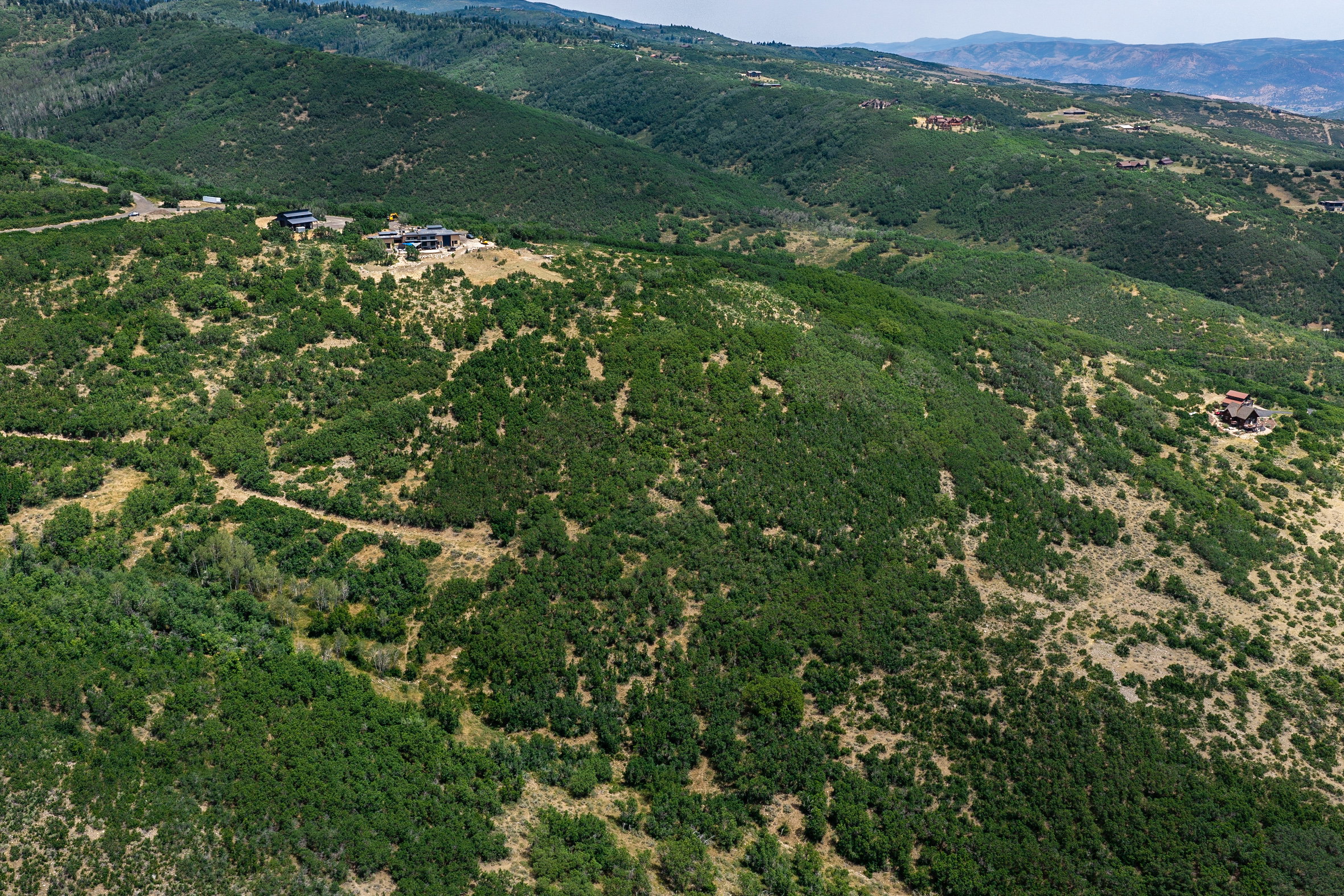 Extensive hillside property featuring a prominent structure with multiple levels, surrounded by substantial natural vegetation