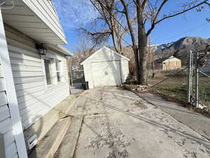 View of driveway with a gate, detached garage, concrete driveway, and a mountain view.
