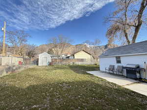 Fenced backyard with a patio area, a shed, and a mountain view