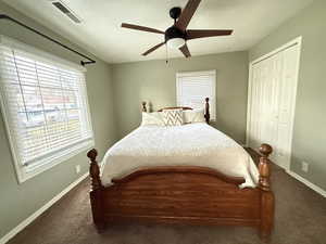 Carpeted bedroom with a ceiling fan and a closet.