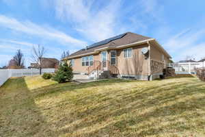 Rear view of property featuring a fenced backyard, solar panels, patio