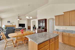 Kitchen featuring lofted ceiling, granite counters, arched walkways, and a center island