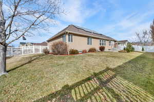 Back of house with a fenced backyard, solar panels, and stucco siding