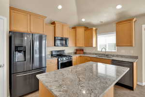 Kitchen featuring  wood finish cabinetry, stainless steel appliances, granite countertops, a kitchen island, and  tile  floors